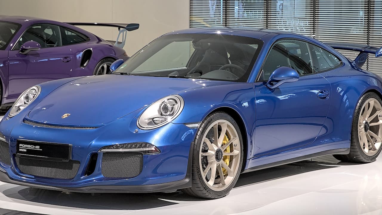 Blue Porsche 911 GT3 with carbon fiber aerodynamic elements and yellow brake calipers in showroom display