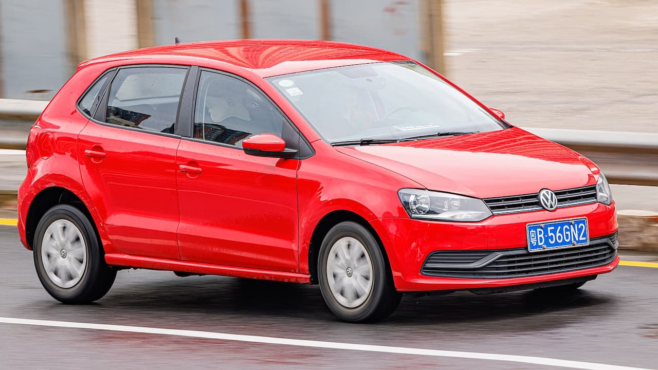 Red Volkswagen Polo driving on wet road with Chinese license plate, featuring VW logo and modern compact car design
