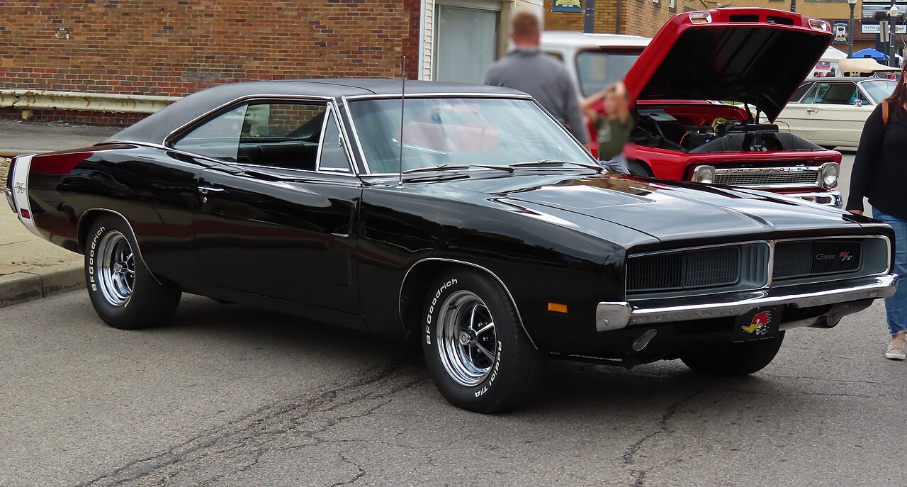 Black 1969 Dodge Charger R/T muscle car parked on street at car show with distinctive grille and racing wheels