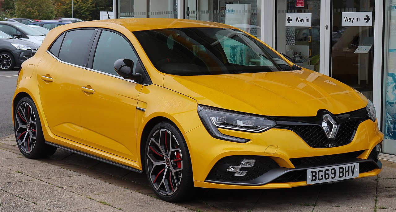 Bright yellow Renault Megane RS with red brake calipers and sporty wheels parked outside dealership
