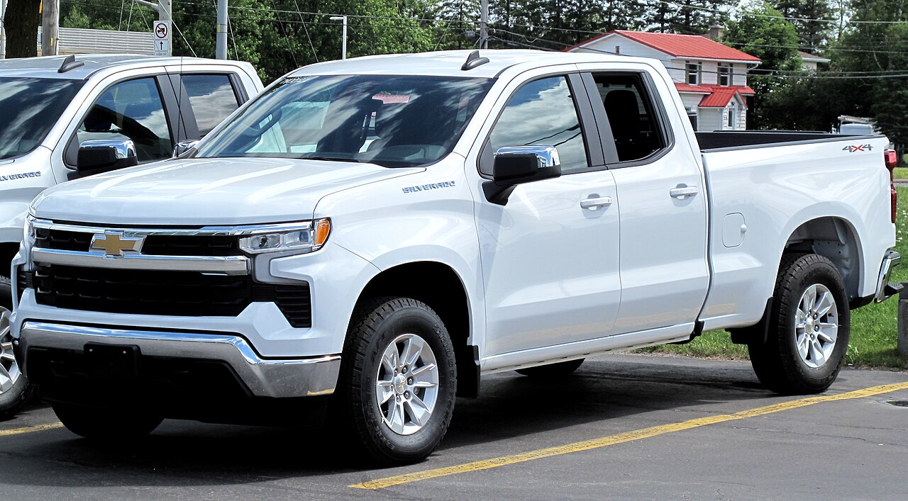 White 2022 Chevrolet Silverado pickup truck parked on street with double cab configuration and alloy wheels in residential area