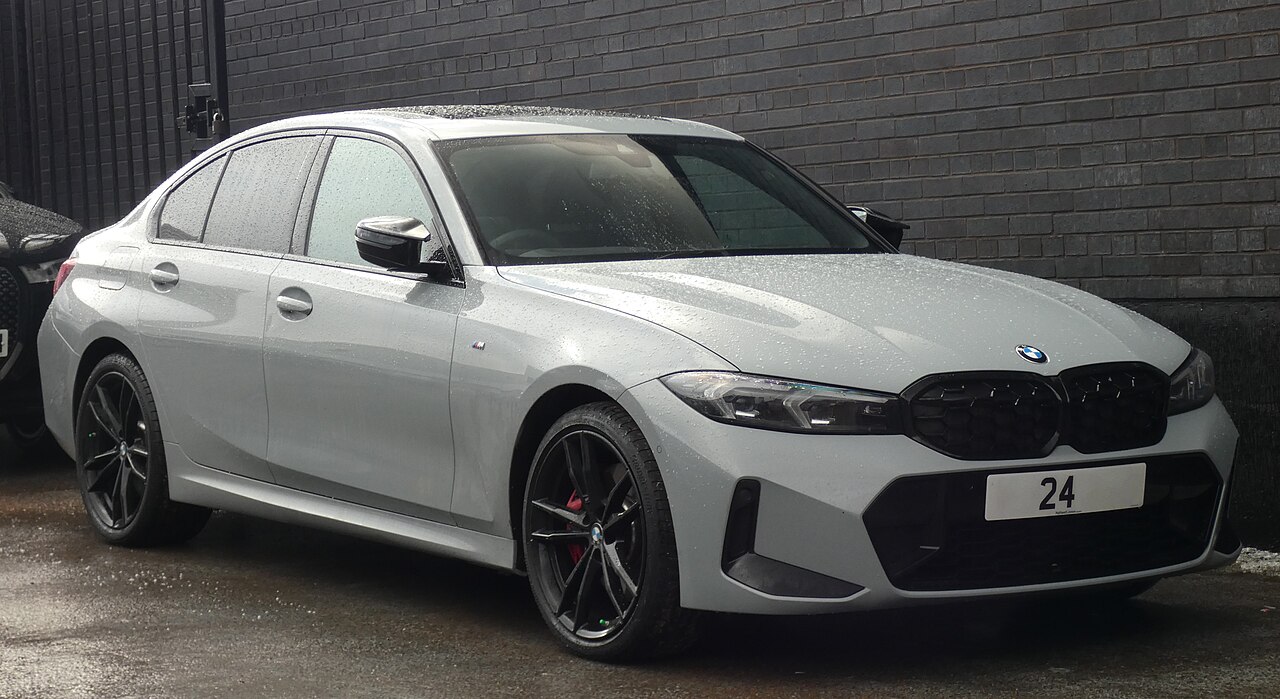 White BMW M340i xDrive with black kidney grille and dark wheels parked against brick wall