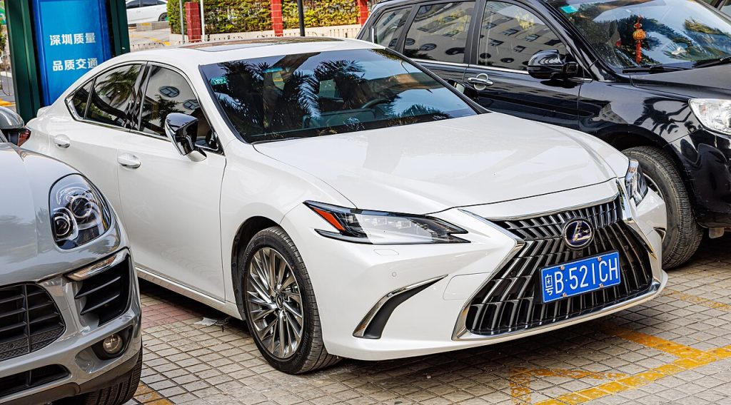 White 2023 Lexus ES with distinctive spindle grille and blue Chinese license plate parked on street