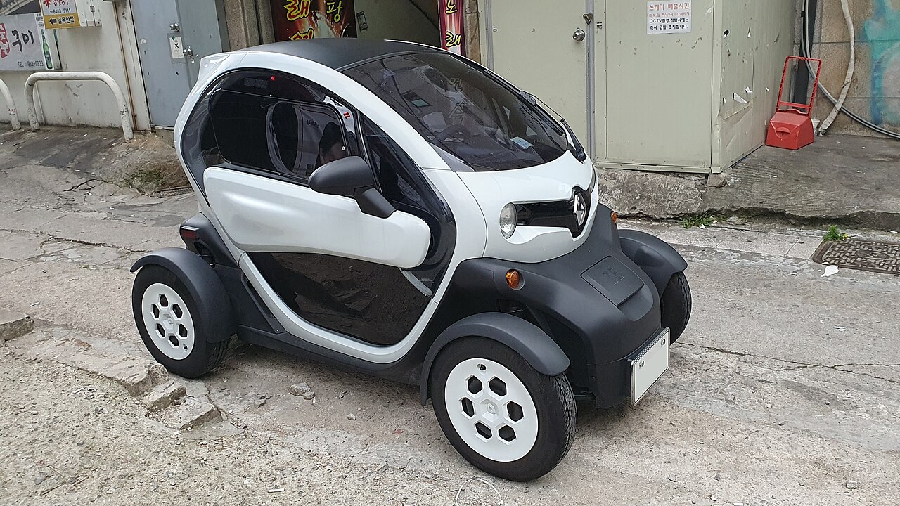 Black and silver Renault Twizy electric microcar with open sides and transparent canopy parked on urban street