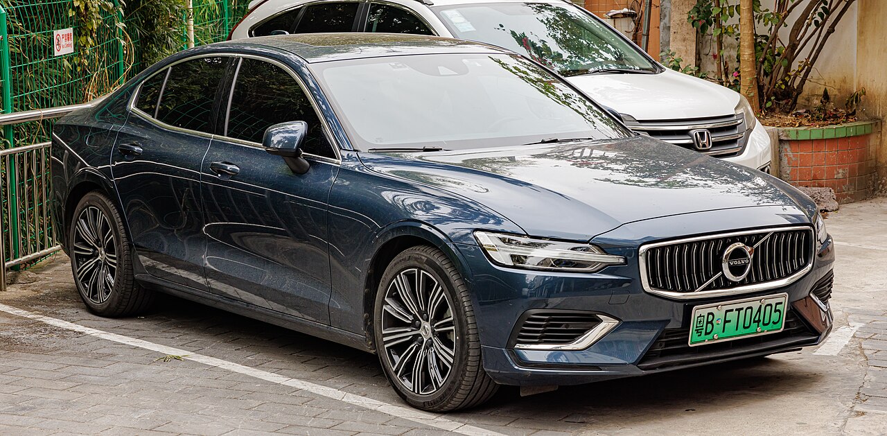 Dark blue Volvo S60 T8 with distinctive grille and alloy wheels parked on street beside white Honda
