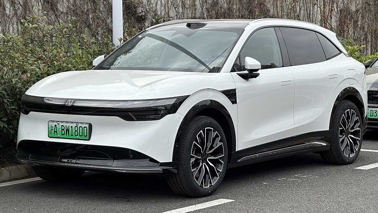 White Zeekr 7X electric vehicle with Golden Battery, with black accents and distinctive styling parked on asphalt with natural vegetation background
