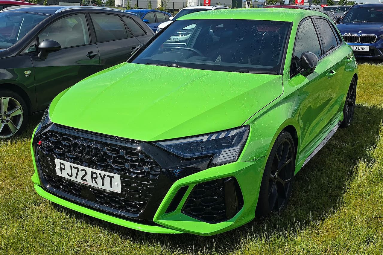 Audi RS3 finished in Kyalami Green with black honeycomb grille and aggressive styling parked on grass at event