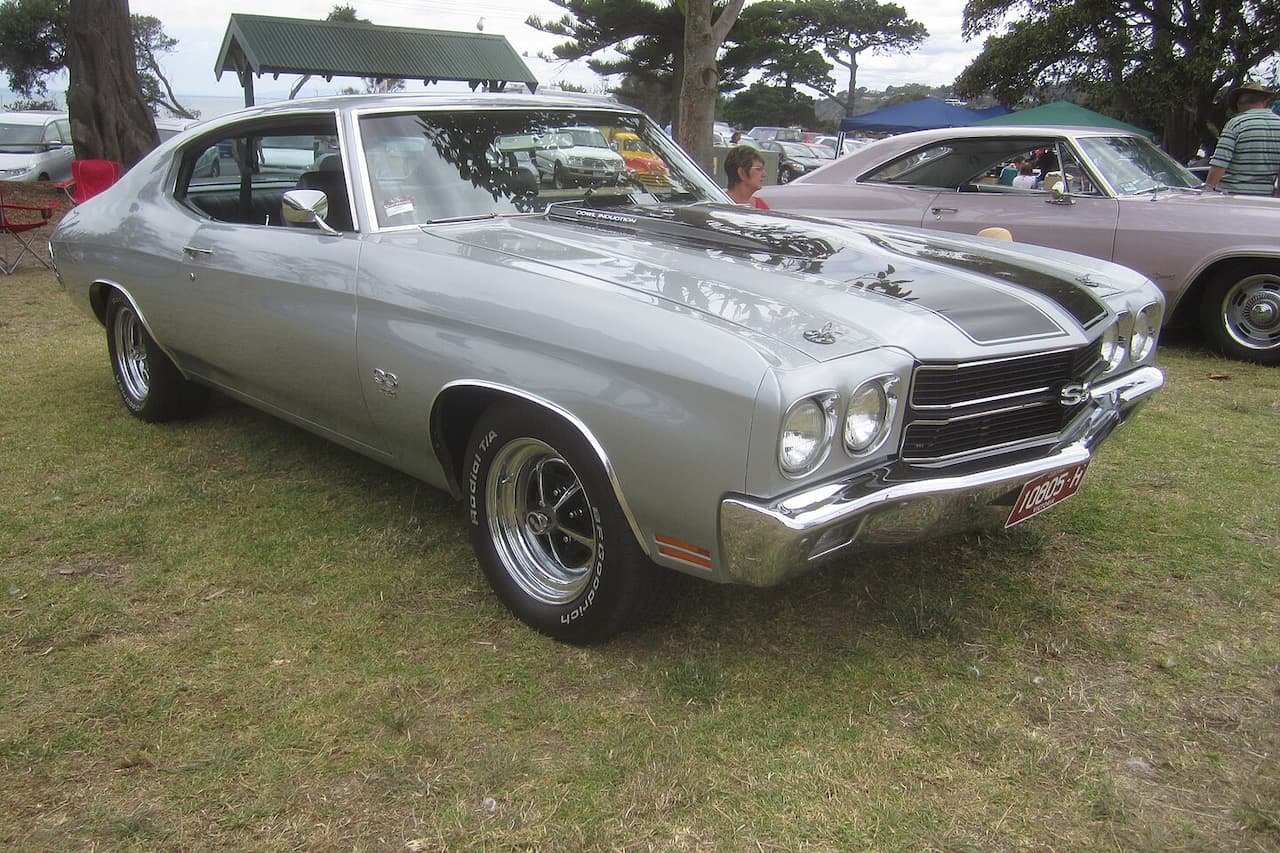 Silver 1970 Chevrolet Chevelle SS muscle car with black racing stripes displayed at outdoor car show event