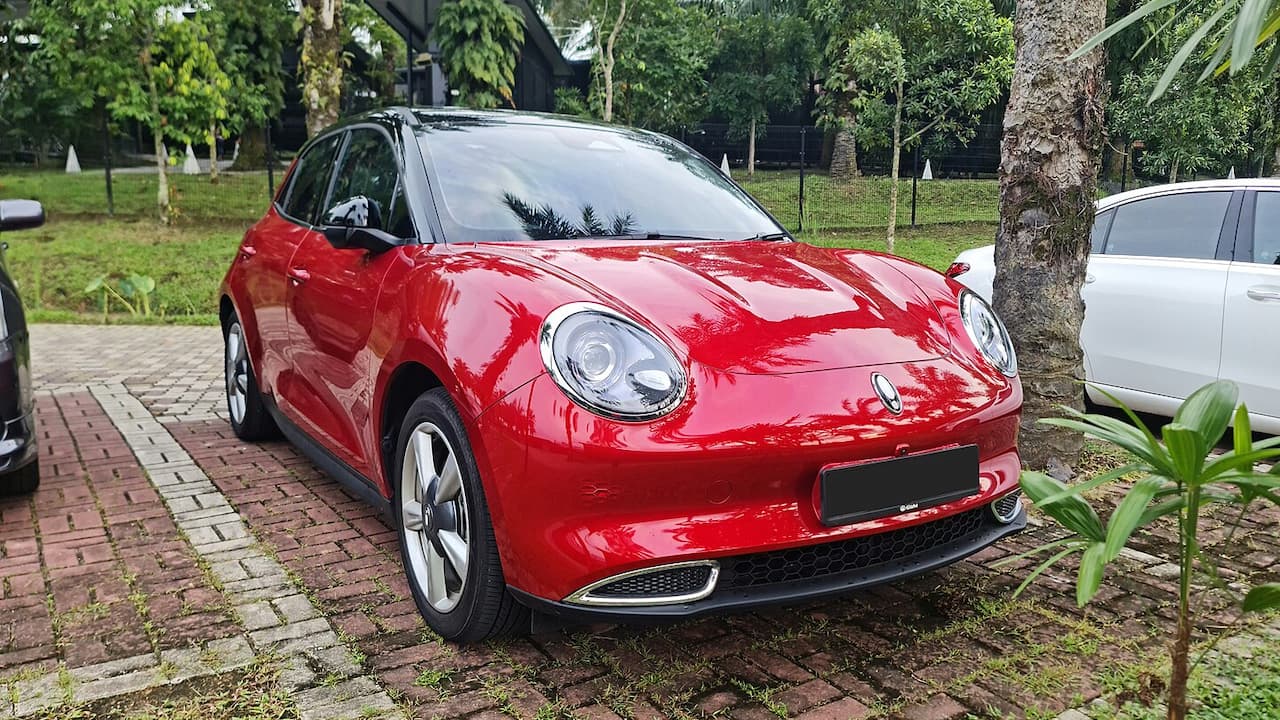 Red GWM Ora City Funk electric hatchback with round headlights and black roof parked on brick pavement