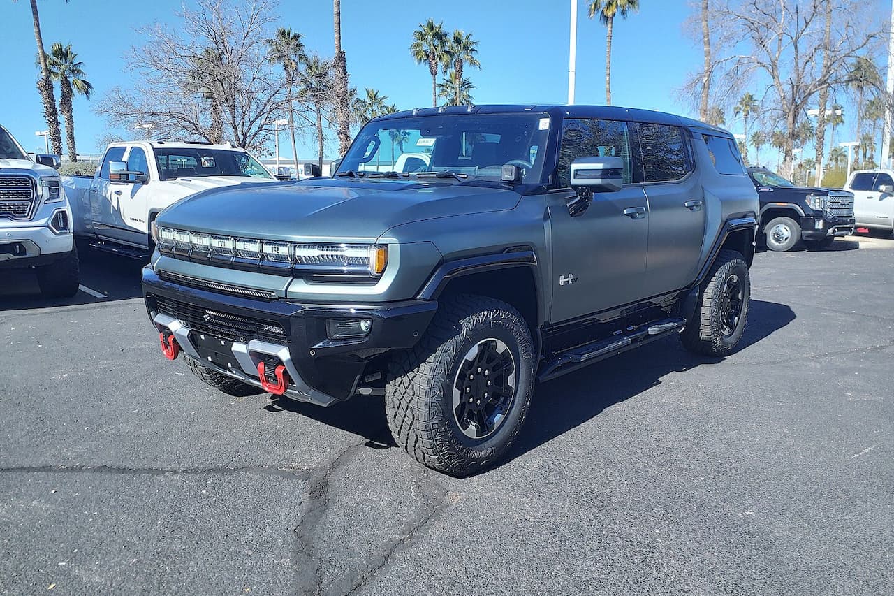 Gray GMC Hummer EV Edition 1 electric pickup truck with red tow hooks and off-road tires in dealership lot