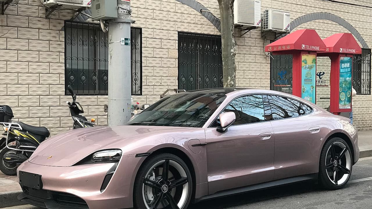 2021 Porsche Taycan parked on street in front of beige brick building with ornate windows and red phone booth