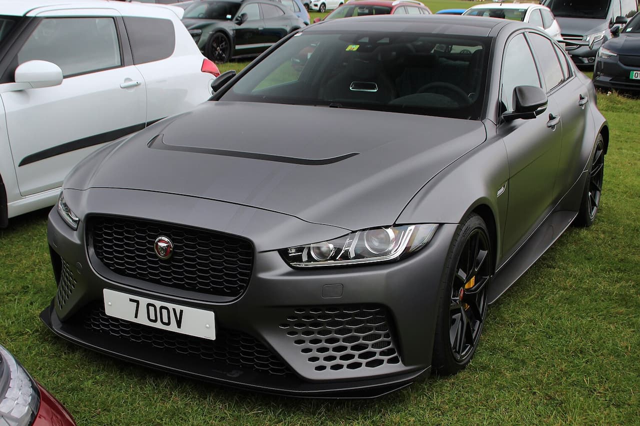 Gray Jaguar XE SV Project 8 with aggressive front splitter and honeycomb grille parked on grass at car show