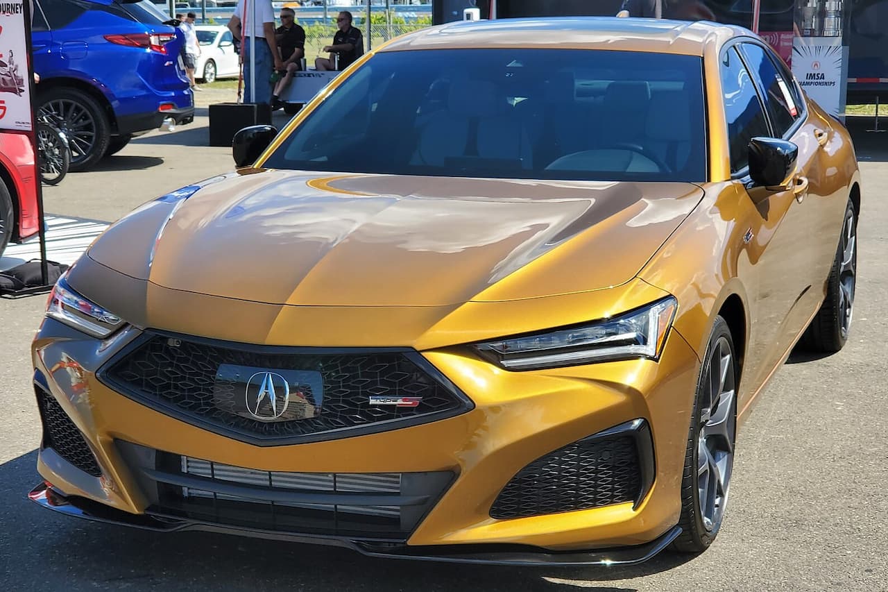 Gold Acura TLX Type S in Tiger Eye Pearl with aggressive front styling and LED headlights at automotive event
