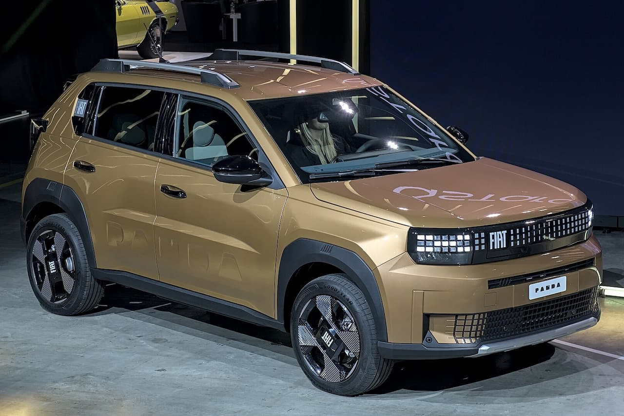 Gold Fiat Grande Panda Electric with pixelated LED grille and black wheels displayed in industrial showroom setting