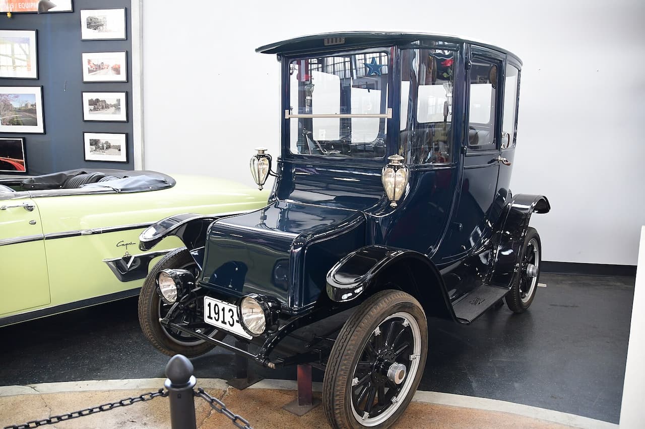 Black 1913 Detroit Electric Car displayed in museum with enclosed passenger cabin, spoked wheels, and vintage automotive styling