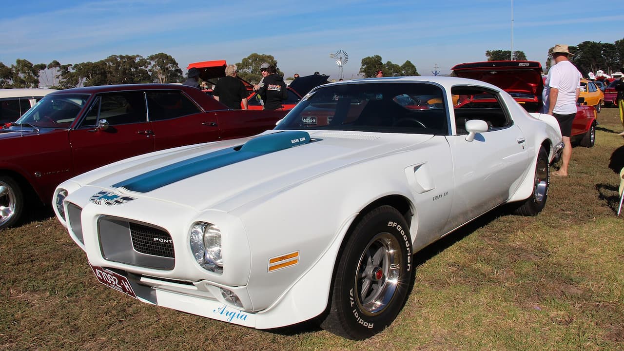 White 1972 Pontiac Firebird Trans Am Super Duty with blue racing stripes at outdoor classic car show