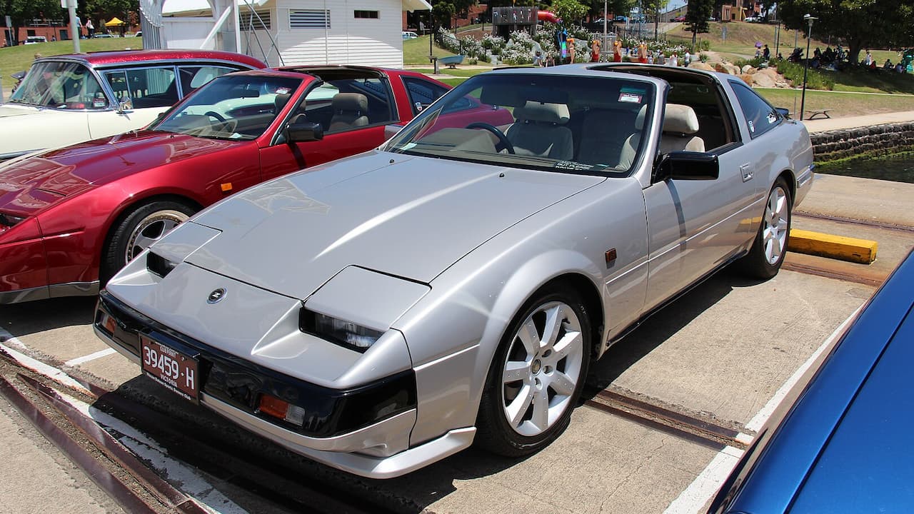Silver 1984 Nissan 300ZX Turbo 25th Anniversary edition parked at outdoor car show with other classic vehicles nearby