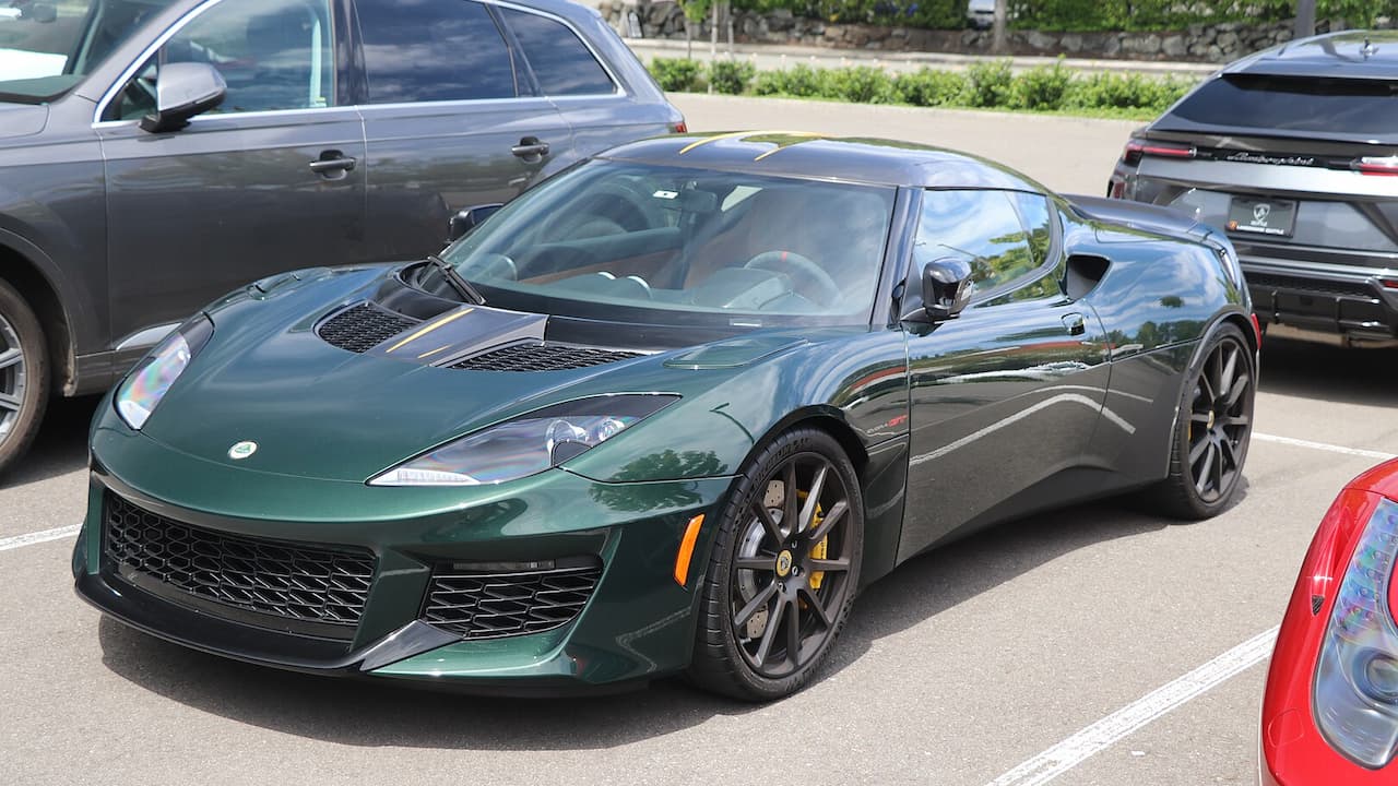 Dark green Lotus Evora GT sports car with black wheels and yellow brake calipers parked in lot