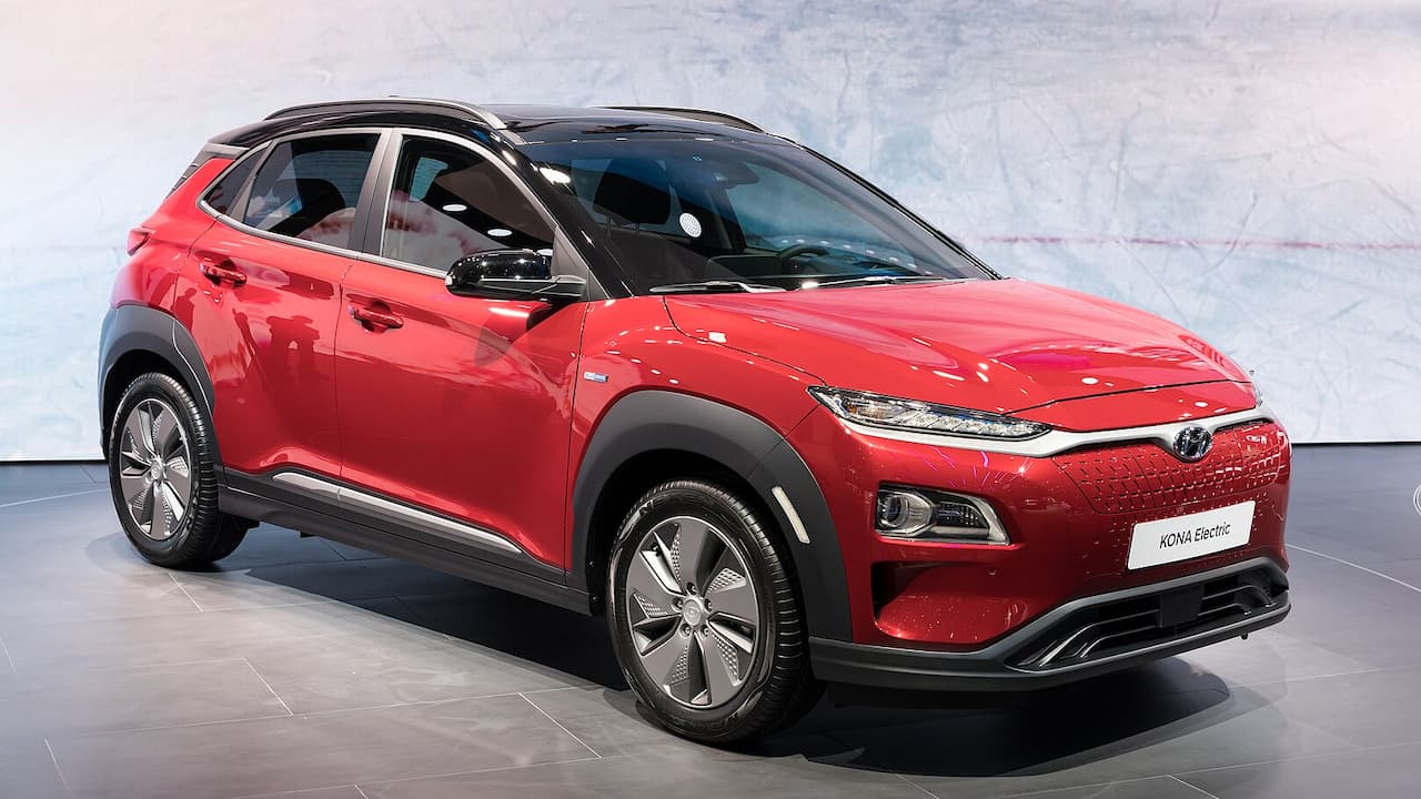 Red Hyundai Kona Electric displayed on showroom floor with distinctive grille, alloy wheels, and "KONA Electric" nameplate