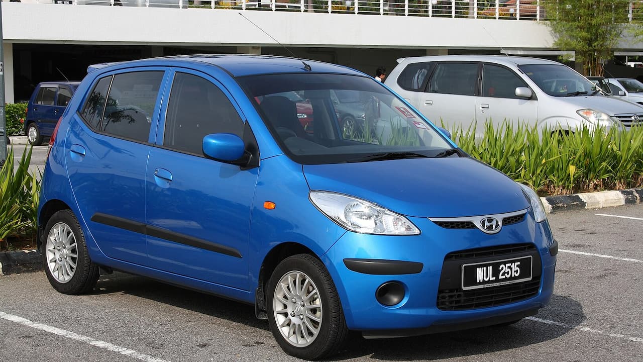 Blue Hyundai i10 parked in Malaysian parking lot with distinctive front grille and multi-spoke alloy wheels