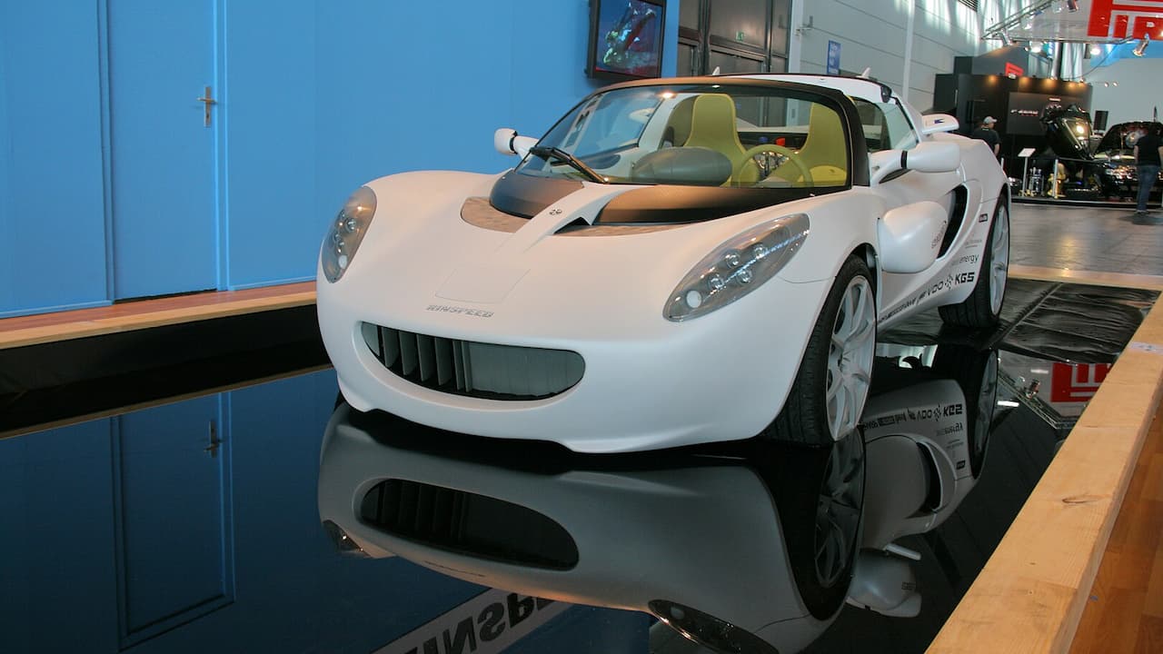 White Rinspeed sQuba displayed on platform in automotive showroom with blue walls and reflective flooring