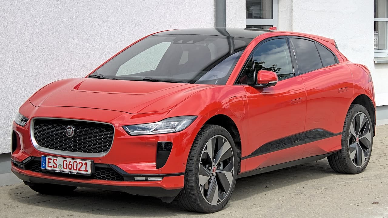 Red Jaguar I-PACE parked in front of white building with German license plate ES-U621