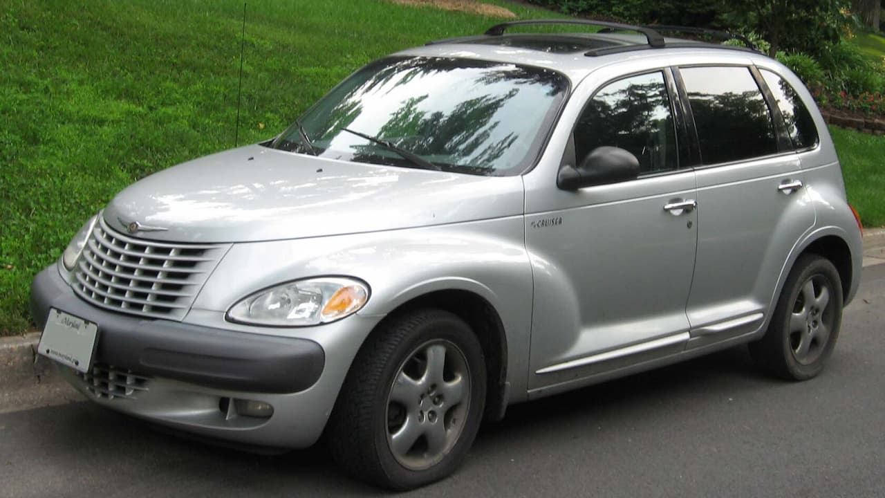 Silver Chrysler PT Cruiser parked on street with distinctive retro styling, sunroof, and green lawn in background