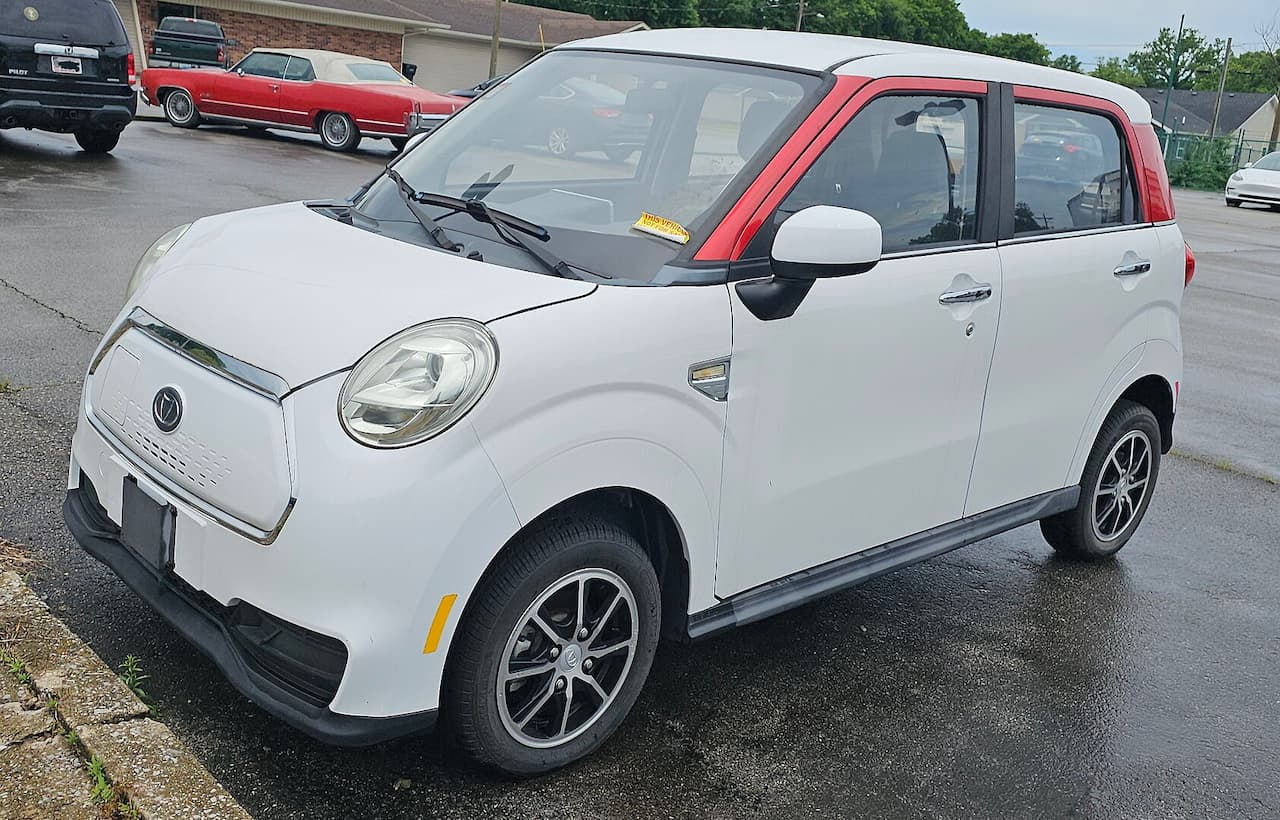 White Kandi K27 electric microcar with red roof trim and alloy wheels parked on asphalt lot