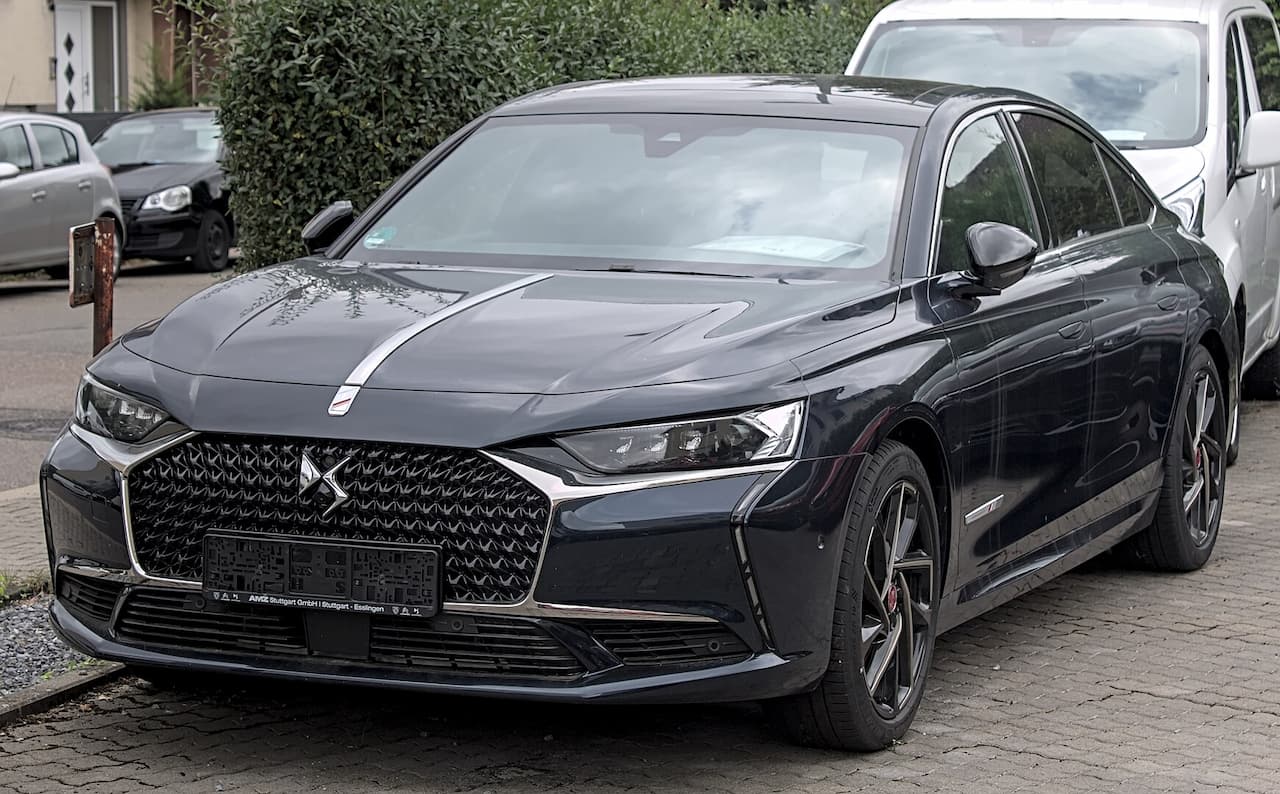 Dark gray DS 9 with distinctive diamond-pattern grille and LED headlights parked on cobblestone street