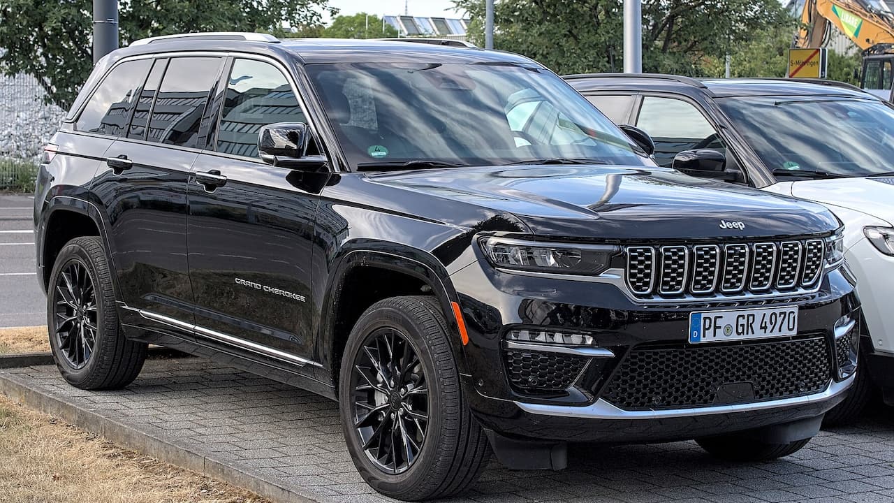 Black Jeep Grand Cherokee parked with distinctive seven-slot grille, dark alloy wheels, and German license plate visible