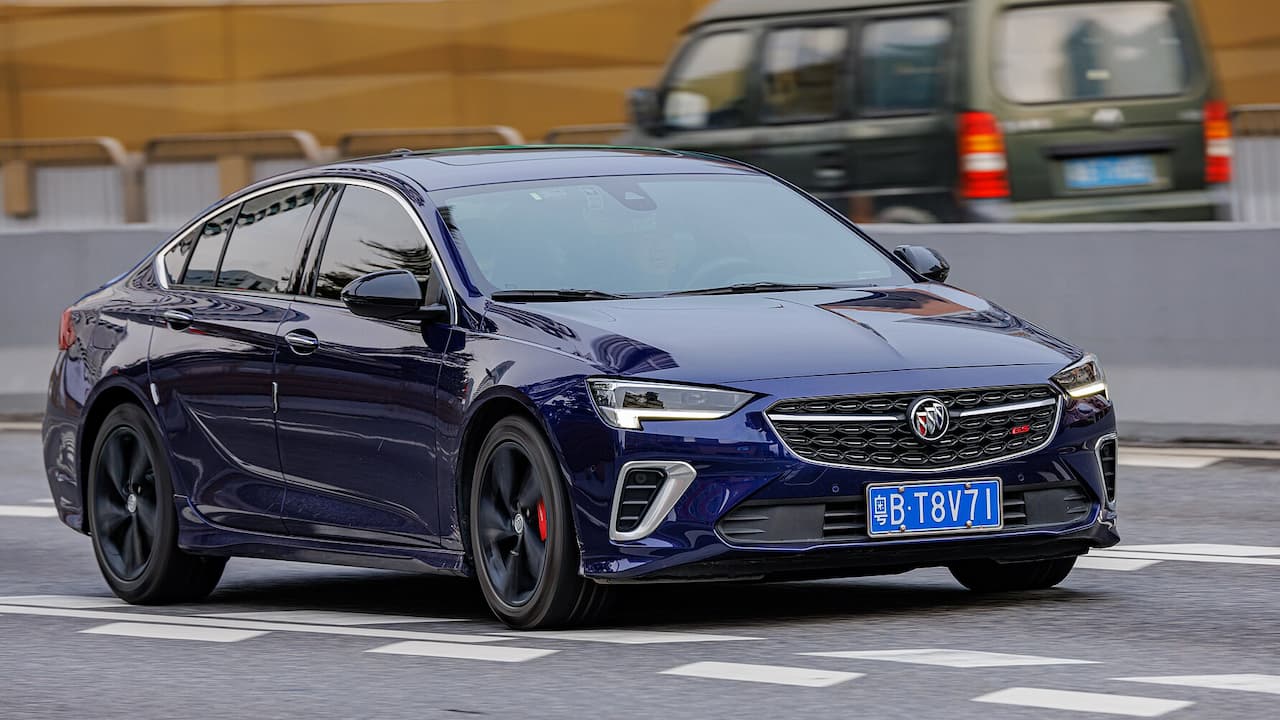 Dark blue Buick Regal GS with black wheels and red brake calipers driving on urban street with Chinese license plate