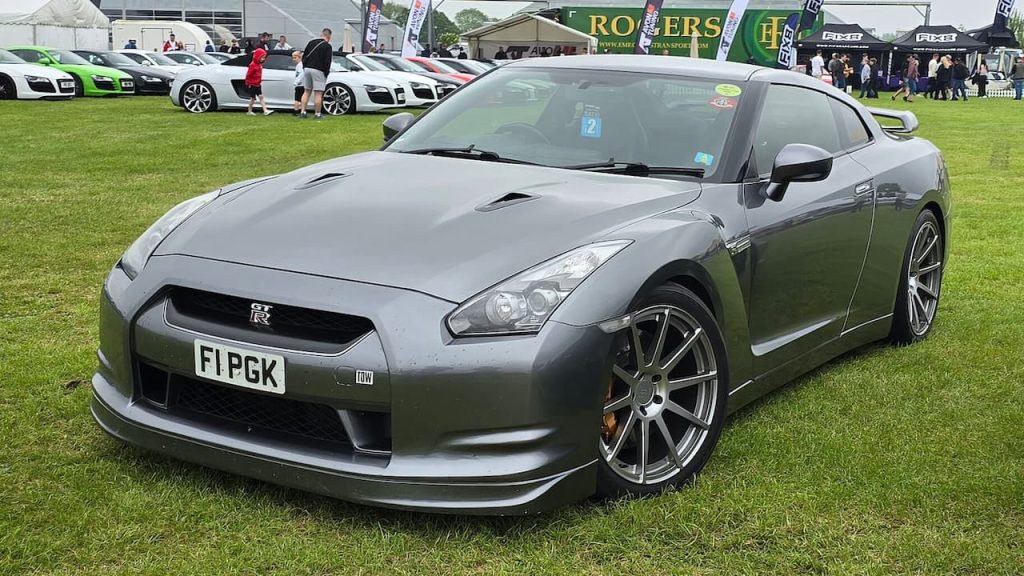 Gray Nissan GT-R sports car with license plate F1PGK parked on grass at outdoor car show event