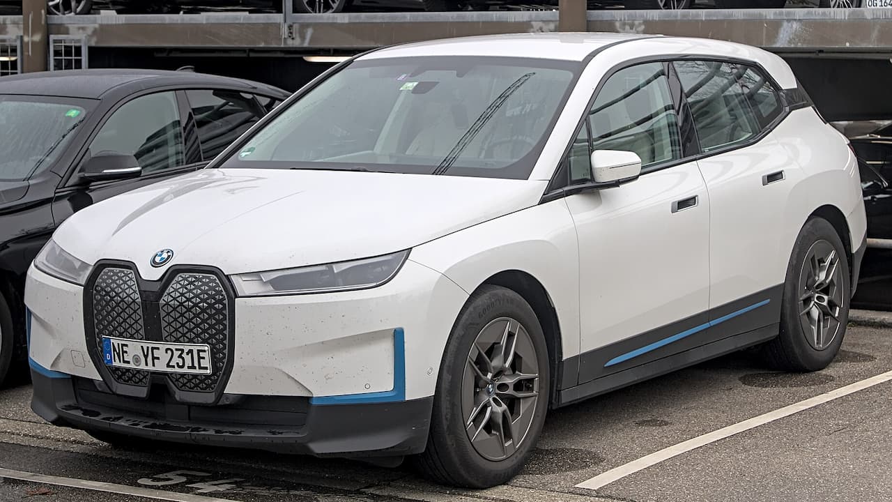 White BMW iX with distinctive large kidney grille and German license plate parked in urban parking area