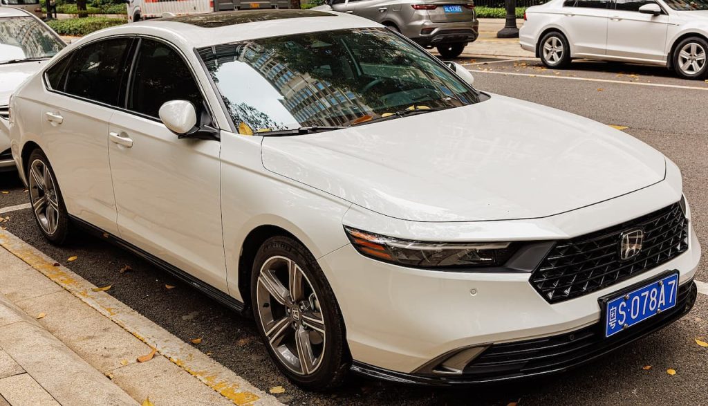 White 2025 Honda Accord with blue license plate parked on city street with other vehicles nearby
