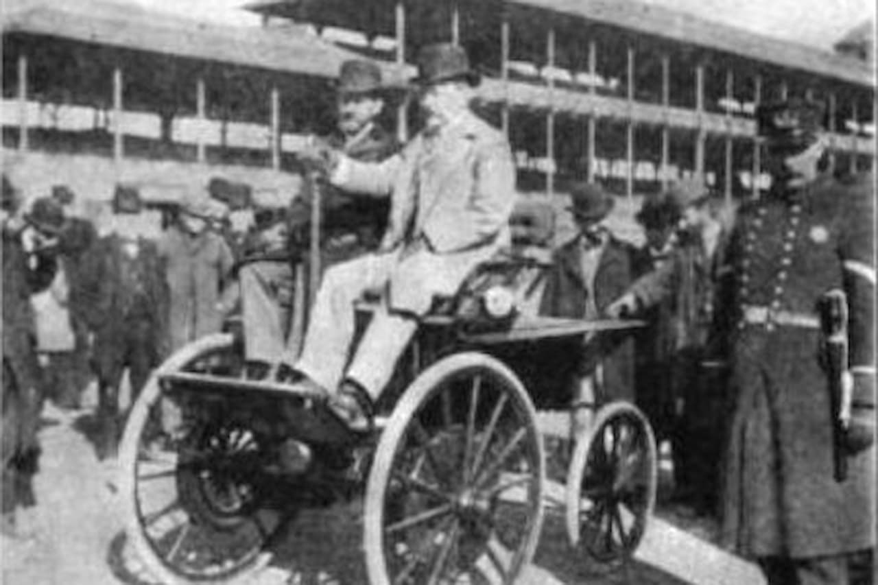 Black and white 1894 photograph showing men with The Electrobat electric vehicle by Salom and Morris in front of buildings