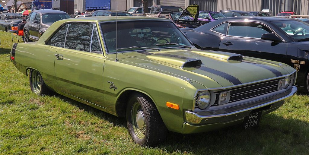 Light green 1972 Dodge Dart Swinger classic car with black hood stripes parked at outdoor show