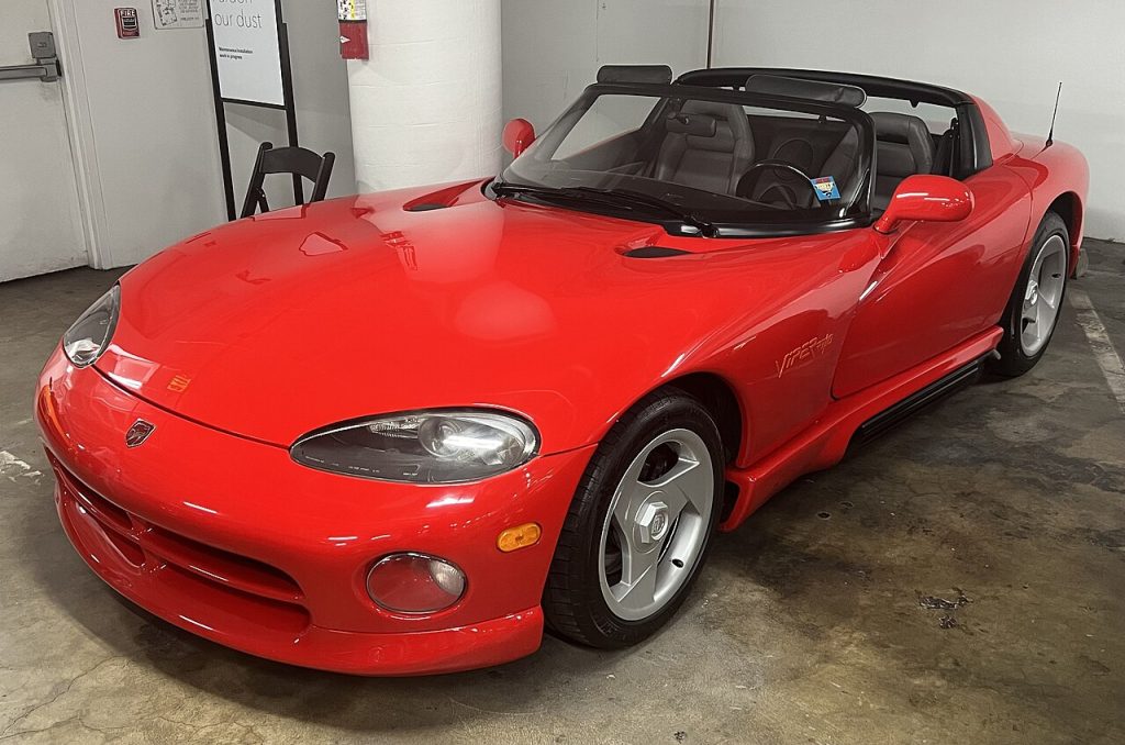 Red 1992 Dodge Viper convertible with black soft top and distinctive long hood parked in indoor garage