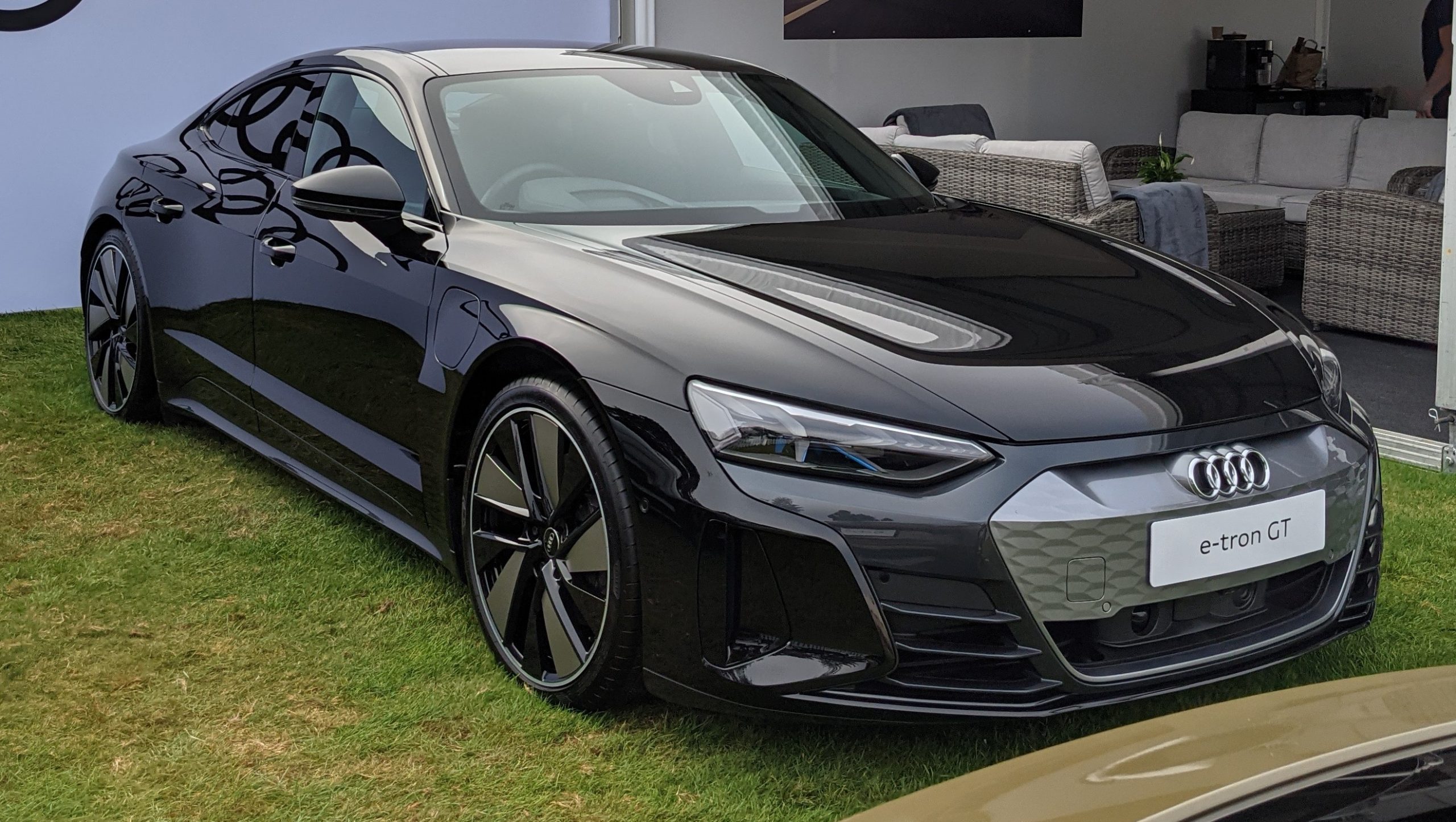 Black Audi e-tron GT with aggressive styling and large wheels displayed on grass at auto show