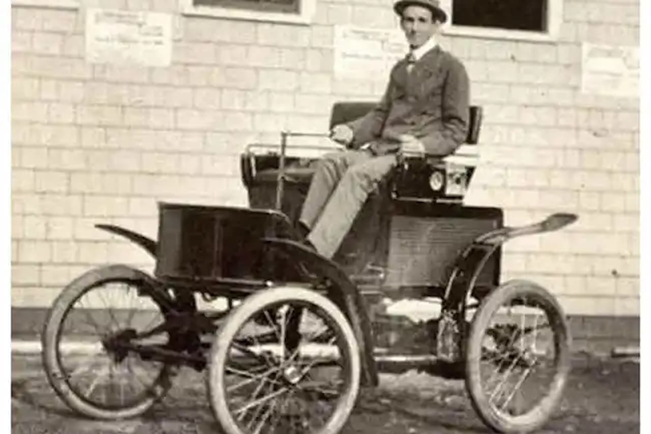 Black and white photograph of man in period clothing sitting on Robert Anderson's 1832 electric carriage with large wheels
