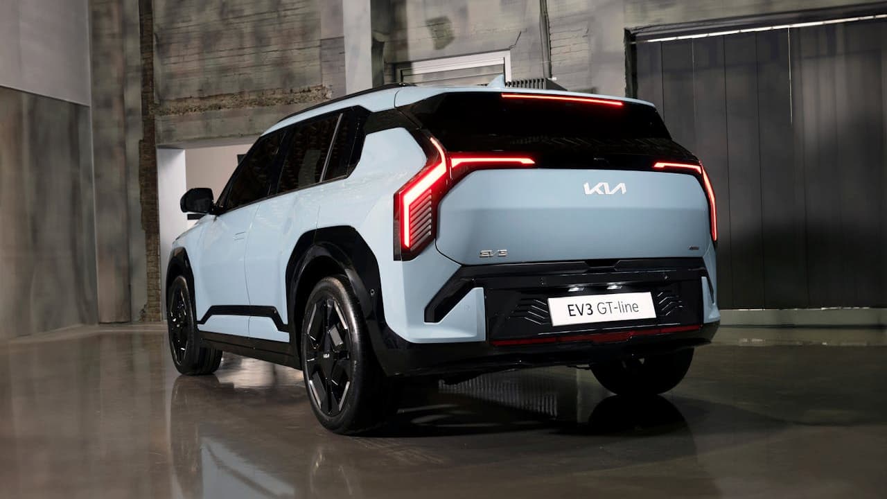 White Kia EV3 GT-line electric SUV parked in modern concrete garage with distinctive red LED taillights illuminated