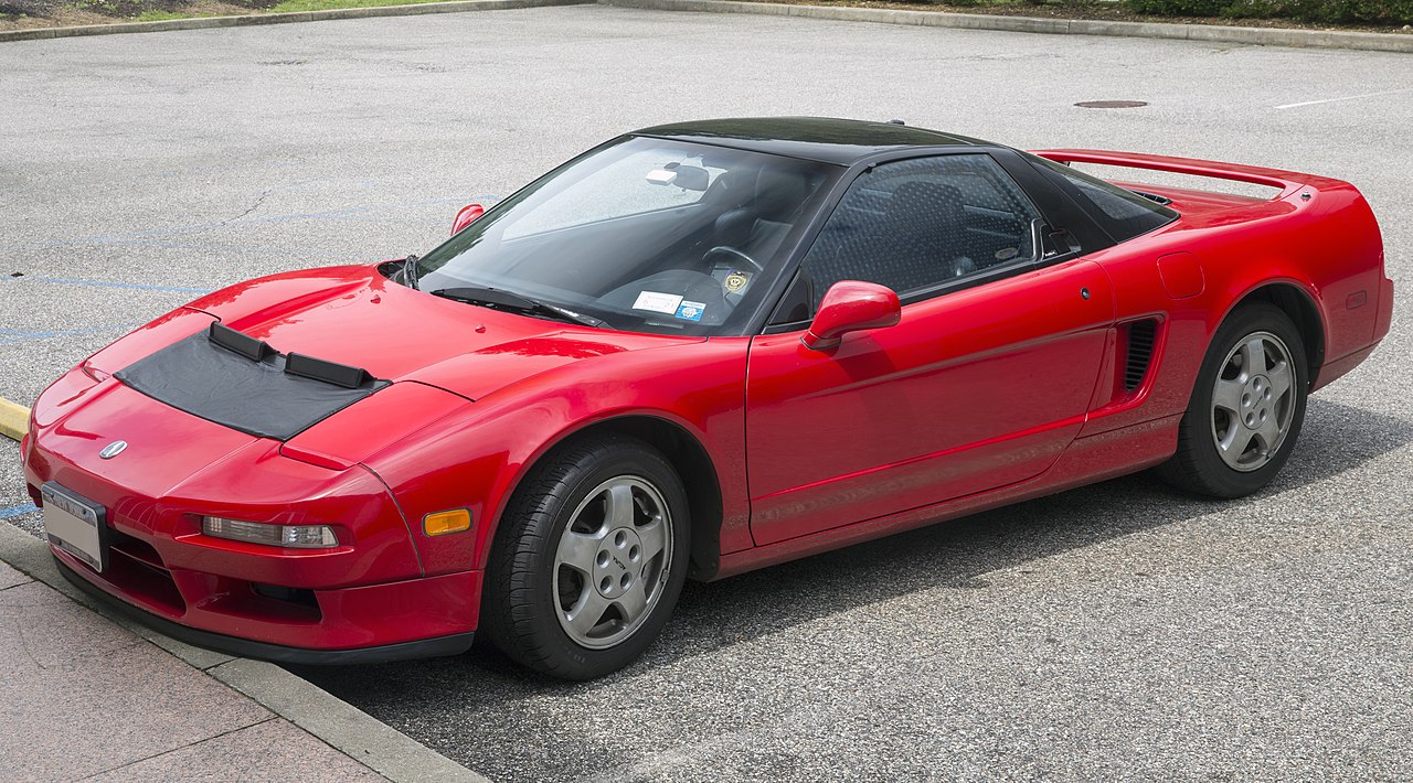 Red 1991 Acura NSX with black roof and silver wheels parked on concrete pavement surface