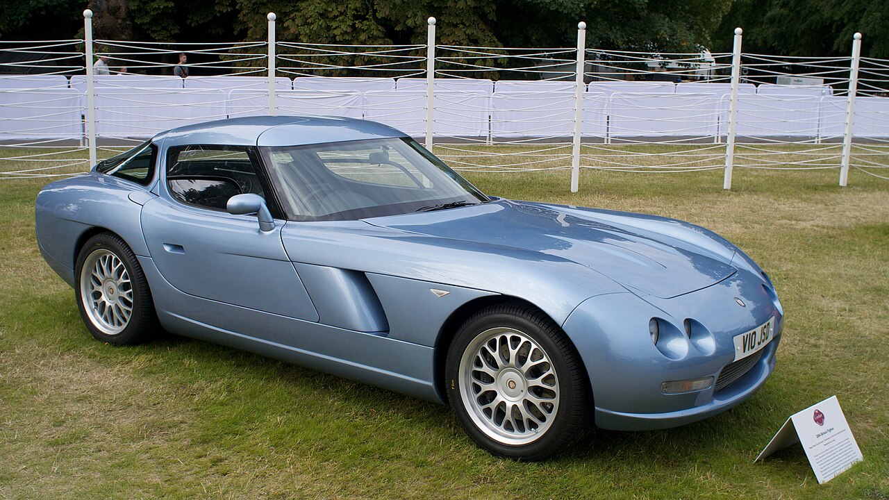 Silver Bristol Fighter sports car with distinctive dual headlights and multi-spoke wheels displayed on grass at car show