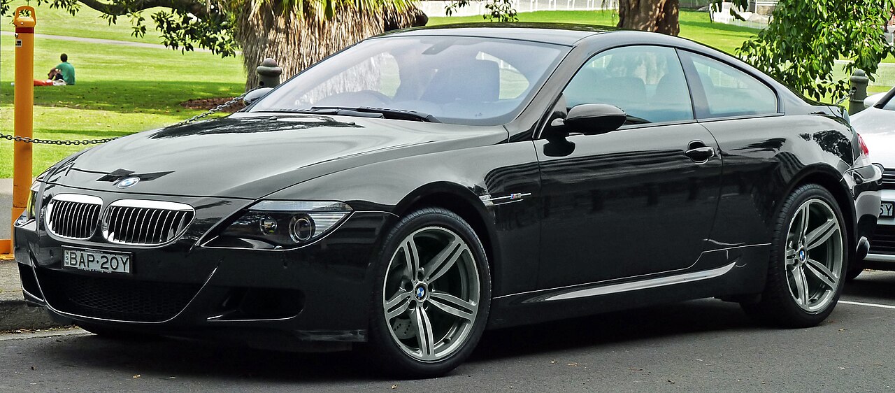 Black 2010 BMW M6 E63 coupe with silver alloy wheels parked on street near park area