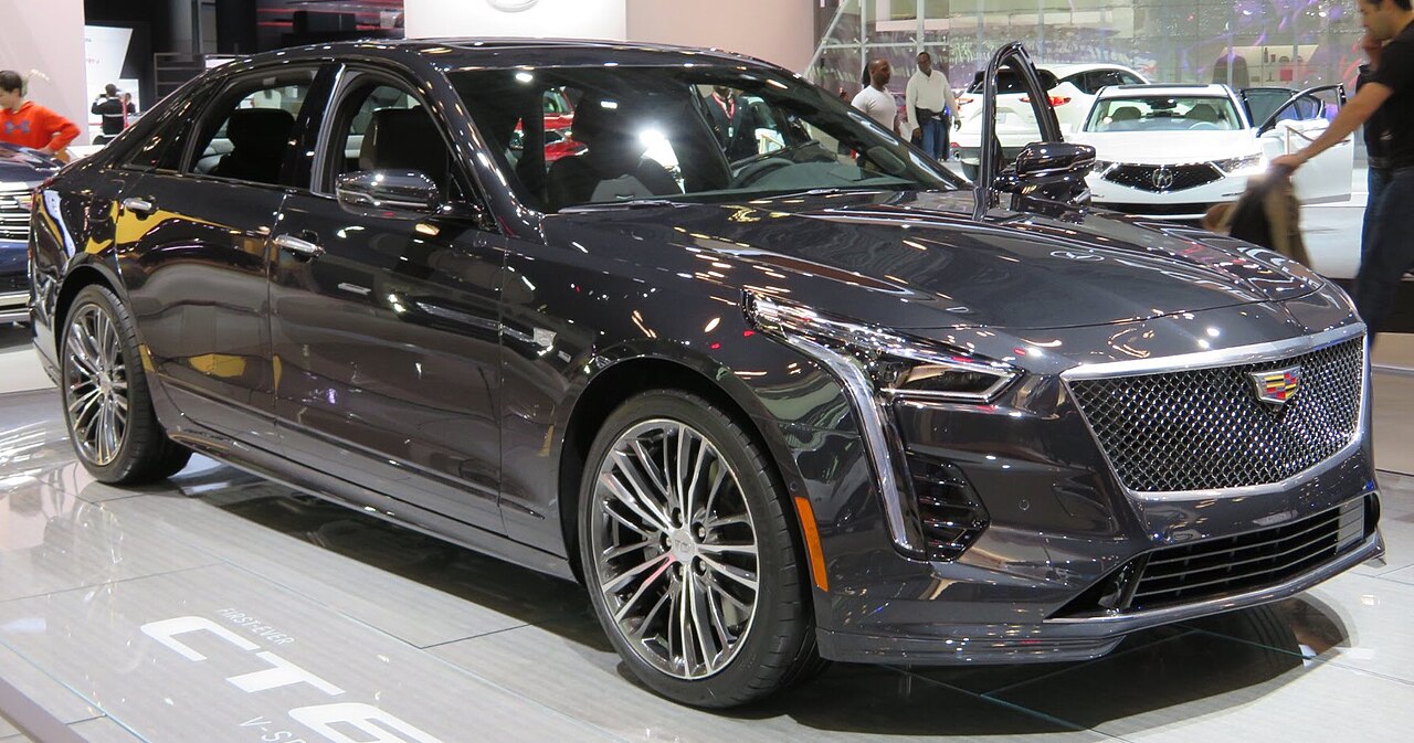 Black Cadillac CT6-V luxury sedan with mesh grille and multi-spoke wheels displayed at indoor auto show