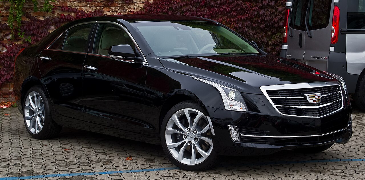 Black Cadillac ATS sedan parked on cobblestone surface with chrome grille, LED headlights, and alloy wheels visible