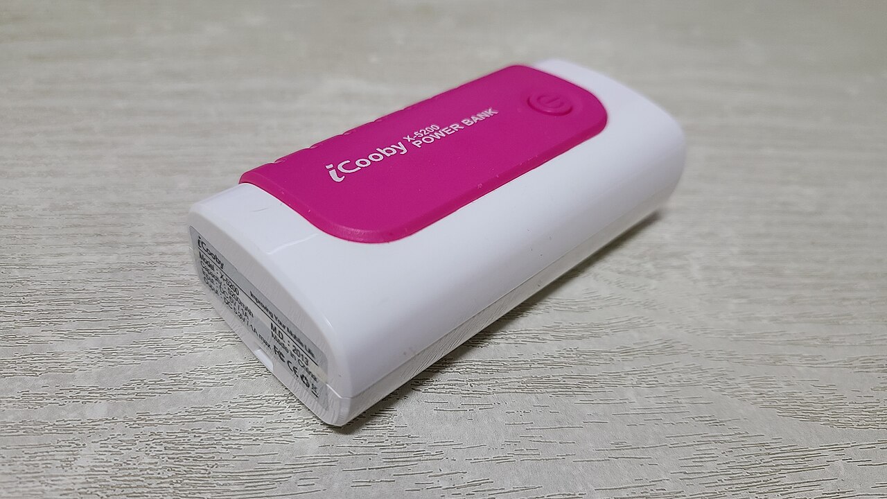 White portable power bank with pink top panel displaying "iCooby" brand name on light wooden surface