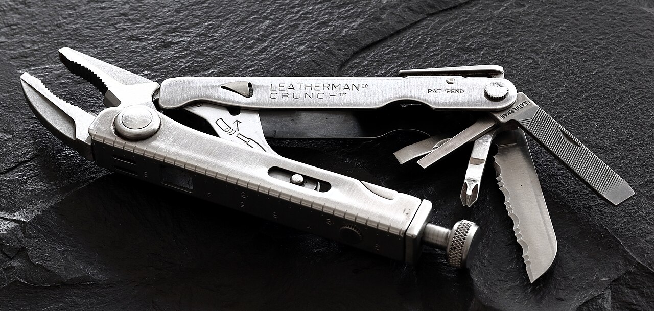 Leatherman Crunch multi-tool with pliers, knife blade, and various tools extended on dark textured surface