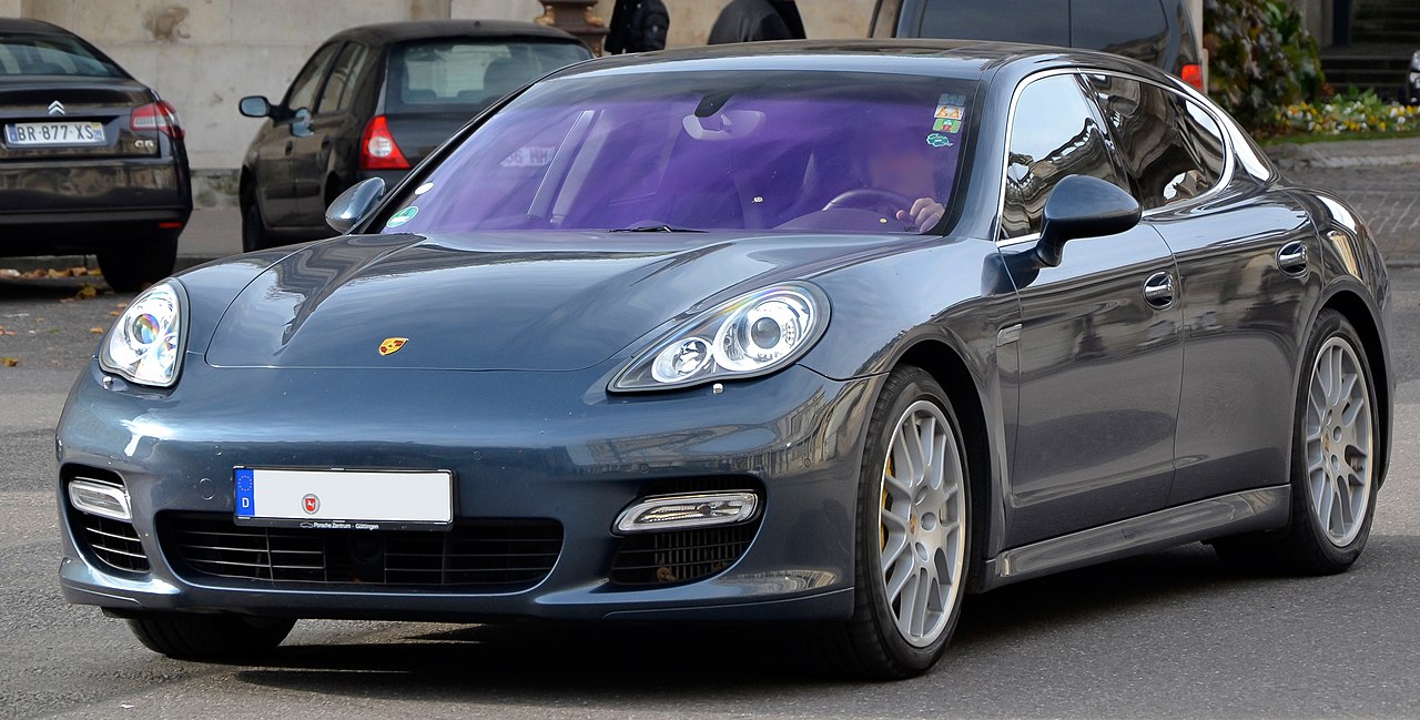 Dark gray Porsche Panamera Turbo sedan with distinctive headlights and alloy wheels parked on European street