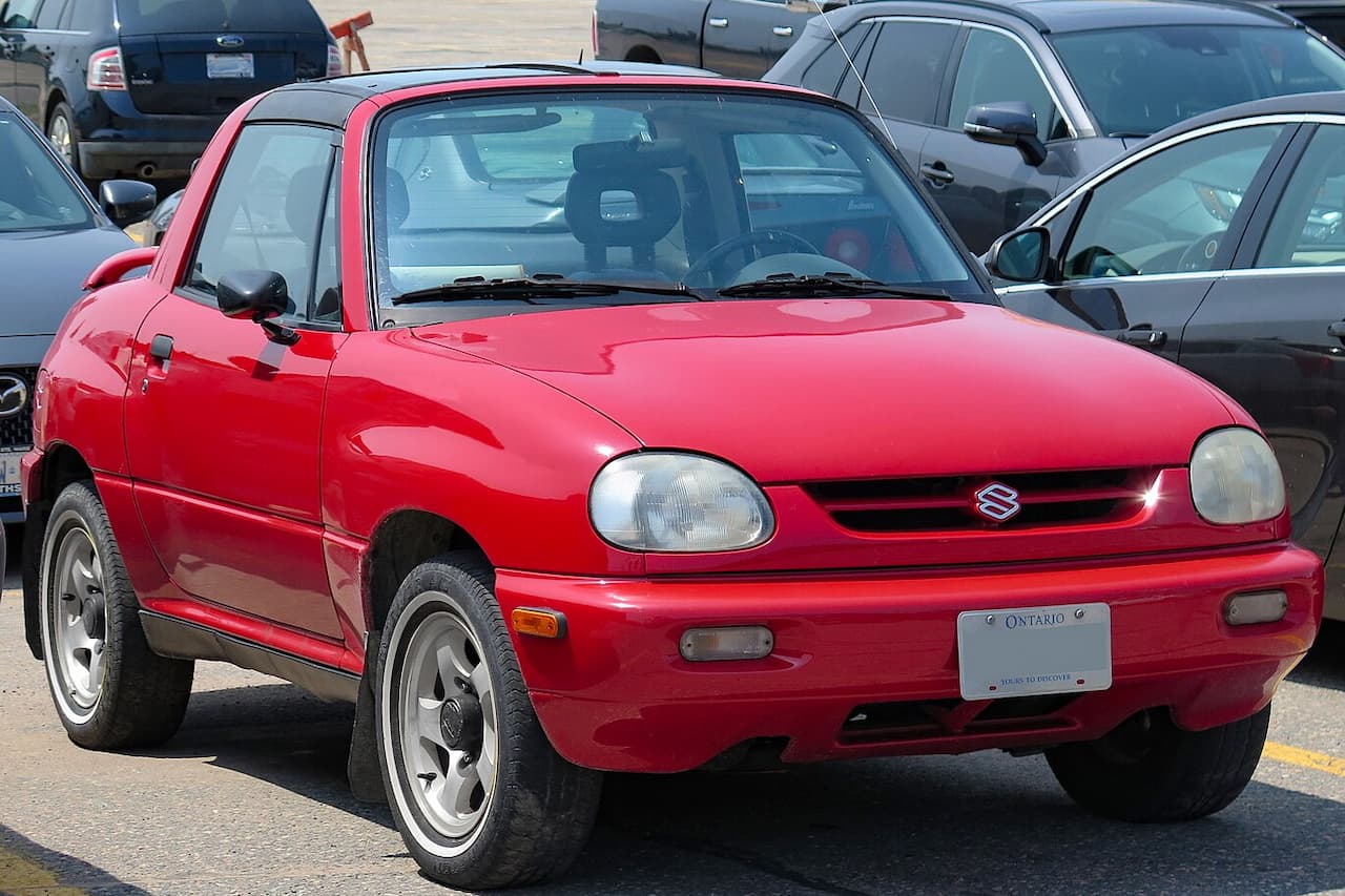 Red Suzuki X-90 compact SUV convertible with Ontario license plate parked in lot surrounded by other vehicles