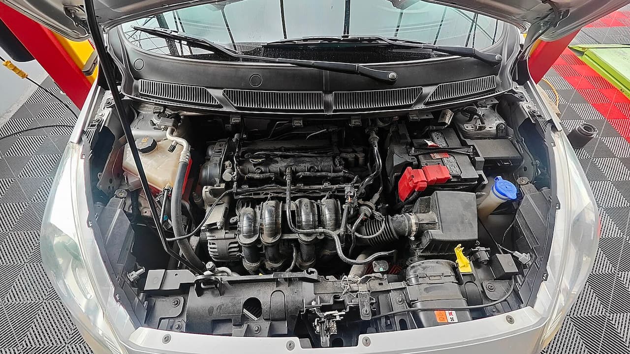 Ford EcoBoost engine bay showing four-cylinder turbocharged engine with intake manifold, red battery terminal, and various automotive components